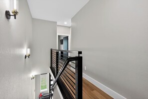 Eine moderne Treppe mit schwarzer Geländer, einer hellgrauen Wand und einem Fenster am unteren Ende.
