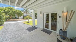A covered entrance with a gravel driveway, a glass door, and a potted plant. - Luxurious Retreat At The Whispering Palms (Wabasso Beach)