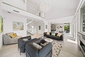 A spacious living area with a modern design, featuring a large sofa set, a coffee table, and a staircase leading to an upper level. - Luxurious Retreat At The Whispering Palms (Wabasso Beach)