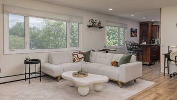 A modern living room with a sectional sofa, a coffee table, and a dining area with a table and chairs.