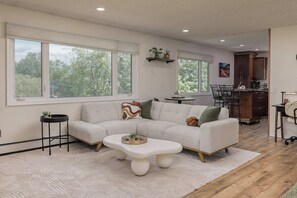A modern living room with a sectional sofa, a coffee table, and a dining area with a table and chairs.