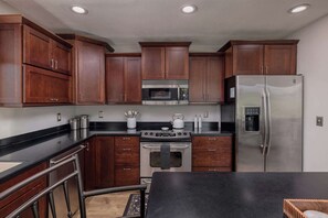 A kitchen with wooden cabinets, a stainless steel refrigerator, a microwave, and an oven.