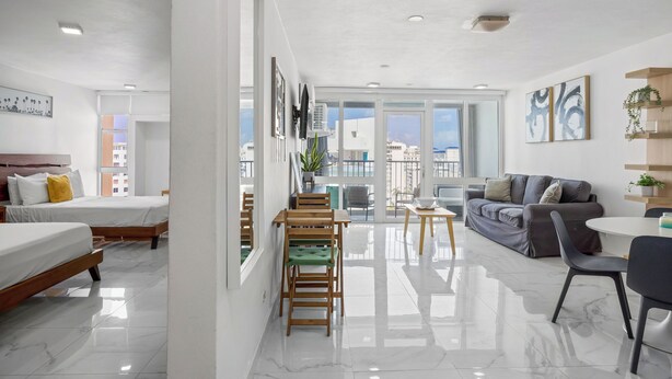 A modern hotel room with a balcony, a dining area, and a living space. - Isla Verde Beachfront ESJ Tower by Otium (Carolina)