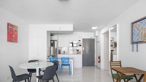 A modern kitchen with white cabinets, a stainless steel refrigerator, and a herringbone-patterned door. - Isla Verde Beachfront ESJ Tower by Otium (Carolina)