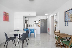 A modern kitchen with white cabinets, a stainless steel refrigerator, and a herringbone-patterned door. - Isla Verde Beachfront ESJ Tower by Otium (Carolina)