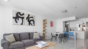A modern living room with a grey sofa, a wooden coffee table, and abstract art on the wall. - Isla Verde Beachfront ESJ Tower by Otium (Carolina)