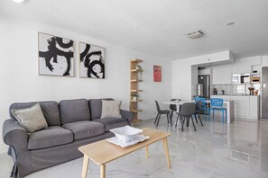 A modern living room with a grey sofa, a wooden coffee table, and abstract art on the wall. - Isla Verde Beachfront ESJ Tower by Otium (Carolina)