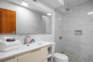 A bathroom with a white sink, mirror, and marble walls. - Isla Verde Beachfront ESJ Tower by Otium (Carolina)