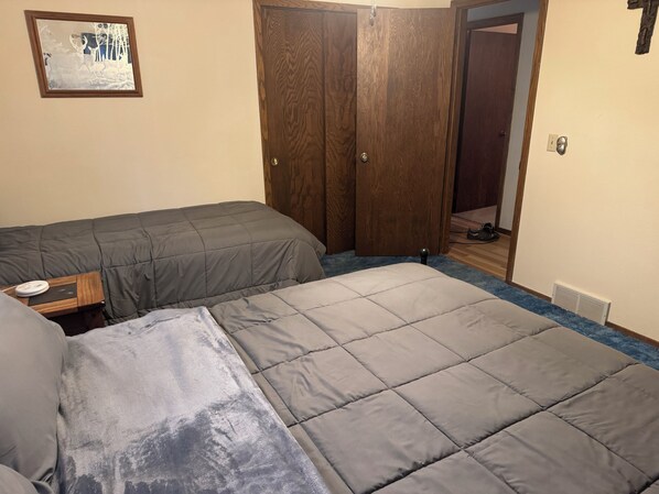 Un dormitorio con dos camas, un armario de madera, una mesita y un cuadro colgado en la pared.