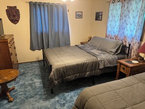 A bedroom with a bed, a nightstand, a lamp, a dresser, and a small table.