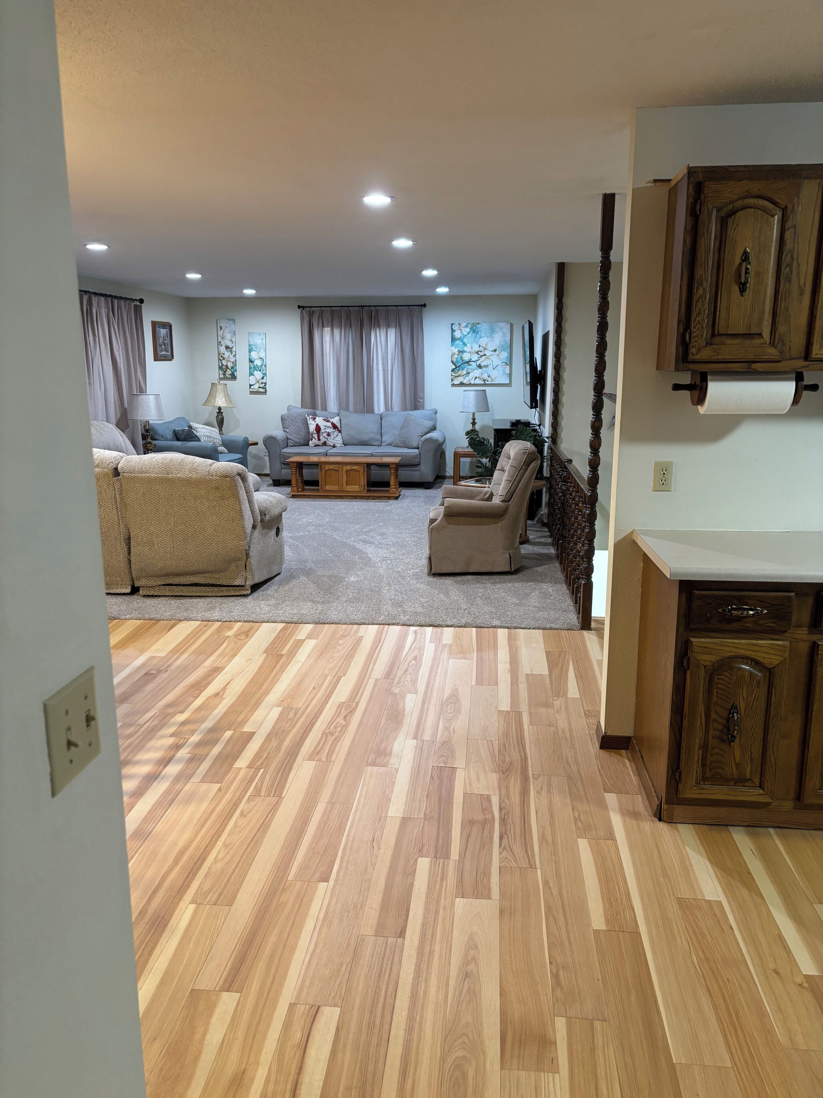Una sala de estar con un sofá, sillones, una mesa de centro y un comedor con un aparador de madera.