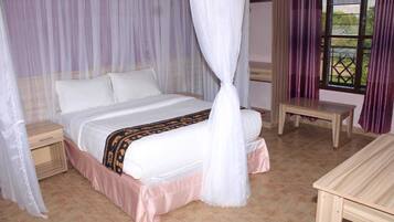Quarto com cama de dossel, mesa de cabeceira de madeira, mesa e janela com cortinas.