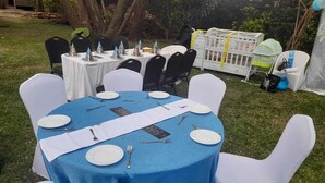 Una mesa redonda con mantel azul, sillas blancas y camino de mesa blanco.
