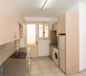 A compact kitchen with a gas stove, a washing machine, and a refrigerator.