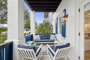A covered patio with a blue sofa, white chairs, and a small table. - PRIVATE BEACH/POOL ACCESS-Newly Renovated-Charming Coastal Getaway (Rosemary Beach)
