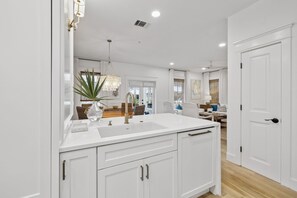 A modern kitchen with white cabinetry, a central island, and a chandelier. - PRIVATE BEACH/POOL ACCESS-Newly Renovated-Charming Coastal Getaway (Rosemary Beach)