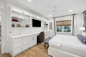 Ein Schlafzimmer mit Bett, Fernseher, Schreibtisch und Stuhl.