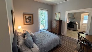 Une chambre avec un lit, une commode et une vue sur la cuisine.