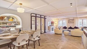 A spacious living area with a dining table set for four, a sofa, and a coffee table. - EXPERIENCE PARISIAN ELEGANCE, LOCATED IN BETWEEN INVALIDES & SAINT-GERMAIN (Paris)