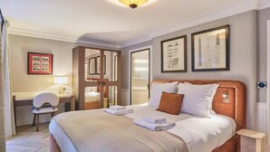 A hotel room with a bed, a desk, a chair, and framed pictures on the wall. - EXPERIENCE PARISIAN ELEGANCE, LOCATED IN BETWEEN INVALIDES & SAINT-GERMAIN (Paris)