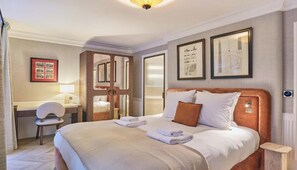 A hotel room with a bed, a desk, a chair, and framed pictures on the wall. - EXPERIENCE PARISIAN ELEGANCE, LOCATED IN BETWEEN INVALIDES & SAINT-GERMAIN (Paris)