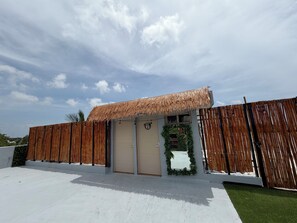 A building with a thatched roof, a bamboo fence, and a door with a wreath. - 11-bedroom mansion for 22 guests, plus a rooftop (Playa del Carmen)