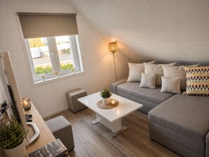 Una sala de estar moderna con sofá, una mesa de centro, una lámpara y una ventana con vistas al exterior.