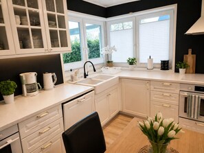 Una cocina moderna con armarios blancos, una silla negra, una cafetera y un lavabo.