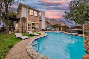 A swimming pool with lounge chairs, a basketball hoop, and a house with a brick facade. - Grand Gem for Large Groups: Pool, Cinema, Playroom (Carrollton)