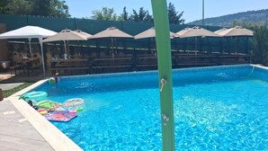 A swimming pool with inflatable toys, a covered seating area, and a green pole.
