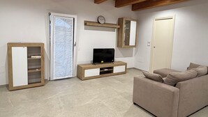 A living room with a television, a sofa, a cabinet, and a door.