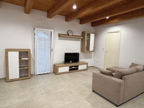 A living room with a television, a sofa, a cabinet, and a door.