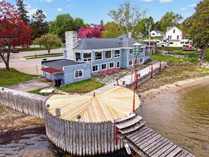 A waterfront property with a dock, a large house with multiple windows, and a small boat docked nearby.