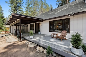 A house with a covered porch, a wooden chair, and potted plants.