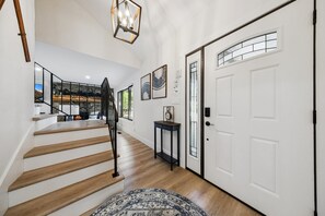 A staircase leading to a second floor, a door with a window, and a small table with a clock.