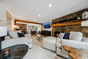 A modern living room with a fireplace, sofas, a coffee table, and a TV mounted on the wall.