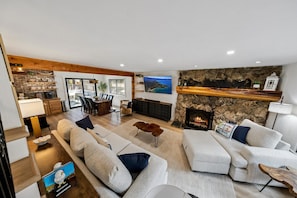 A modern living room with a fireplace, stone wall, and a view of the outdoors.