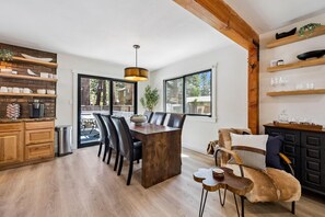 A modern kitchen with a wooden island, black chairs, and a dining table.