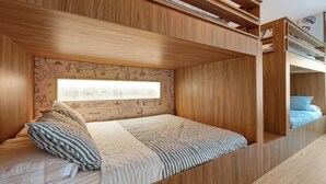 A bunk bed with a built-in desk, a window with a view of the outdoors, and a wooden wall with a desert-themed mural. - 1 bedroom apartment near Disney and Universal (Orlando)
