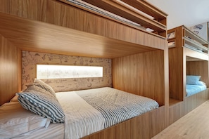 A bunk bed with a built-in desk, a window with a view of the outdoors, and a wooden wall with a desert-themed mural. - 1 bedroom apartment near Disney and Universal (Orlando)