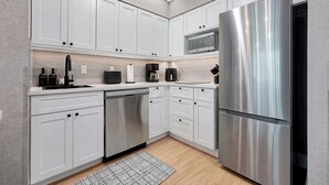 A modern kitchen with white cabinets, a stainless steel refrigerator, a dishwasher, and a microwave. - 1 bedroom apartment near Disney and Universal (Orlando)
