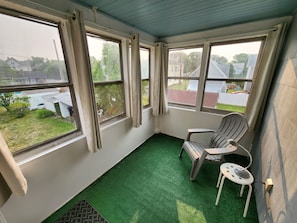 A room with a green artificial turf floor, a white chair, and a small table. - Cozy and Sunny 1-bedroom Apartment in Holyoke (Holyoke)
