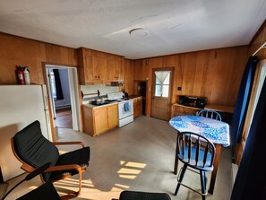 A compact kitchen with wooden cabinets, a stove, and a dining area with a table and chairs. - Cozy and Sunny 1-bedroom Apartment in Holyoke (Holyoke)