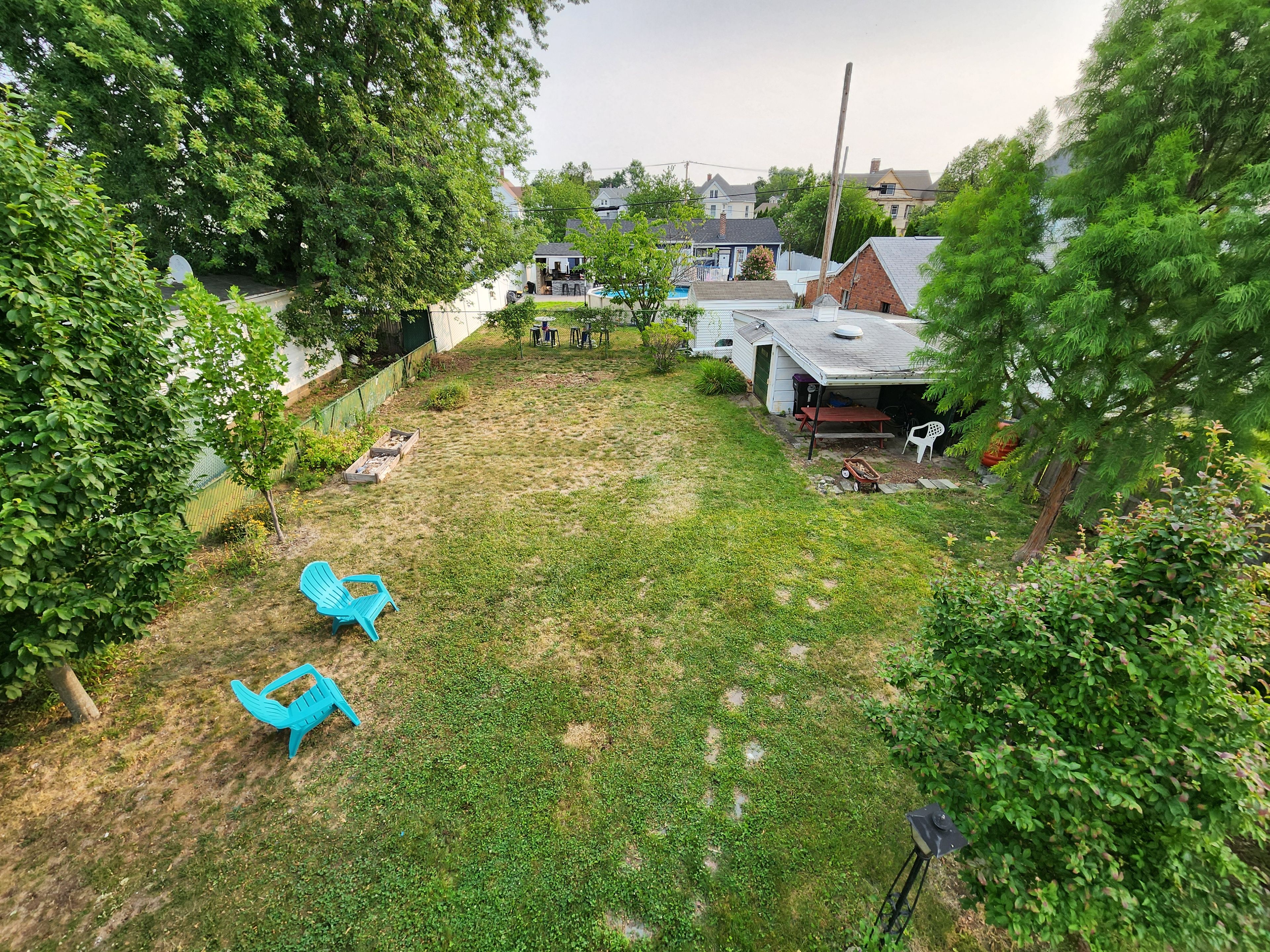 A backyard with a lawn, a play area with a swing set, and a covered patio area.