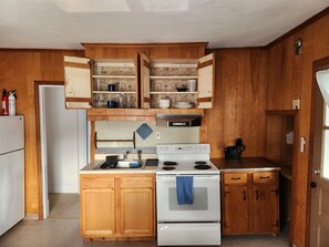 A kitchen with wooden cabinets, a white stove, and open shelves above. - Cozy and Sunny 1-bedroom Apartment in Holyoke (Holyoke)