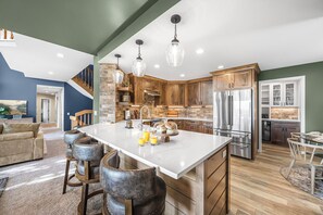 A modern kitchen with a central island, wooden cabinets, and stainless steel appliances. - Stunning 5 Bed 3 Bath-Golf Simulator-2 Hot Tubs-2 Fire Pits-Theater (Bellaire)