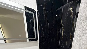 Une salle de bain avec un lavabo blanc, un meuble-lavabo noir et un miroir au-dessus.