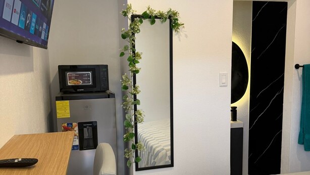 Une chambre à coucher avec un lit, un bureau et une chaise, une télévision, un miroir et une porte.
