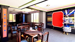 Un comedor con mesas y sillas de madera, un detalle decorativo rojo y un papel tapiz estampado.