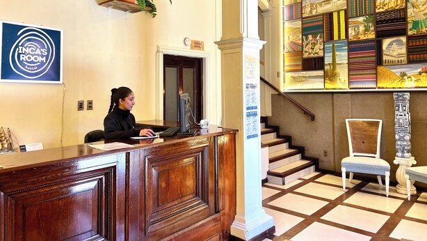 Una recepción con una computadora, una planta y un cartel que dice 'INCA'S ROOM hostel'.